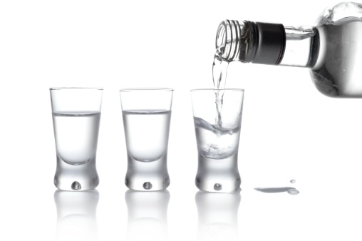 Close-up view of bottle and glasses of vodka poured into a glass isolated on white