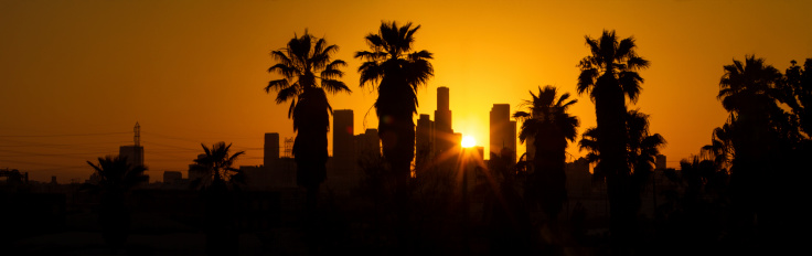 Silhouetted Los Angeles skyline at sunset.