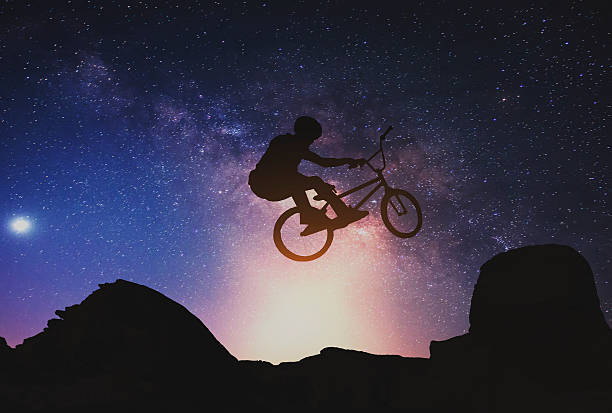 istock Riding a bike performing on Mountain with Milky way. 505991360