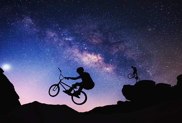 istock Riding a bike performing on Mountain with Milky way. 505991450