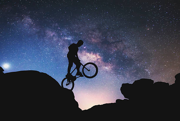 istock Riding a bike performing on Mountain with Milky way. 505991536