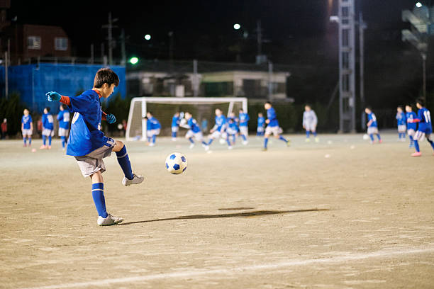 Youth Soccer Player in Tokyo Japan A teenage Japanese boy playing soccer at night in Tokyo, Japan. child japanese culture japan asian ethnicity stock pictures, royalty-free photos & images