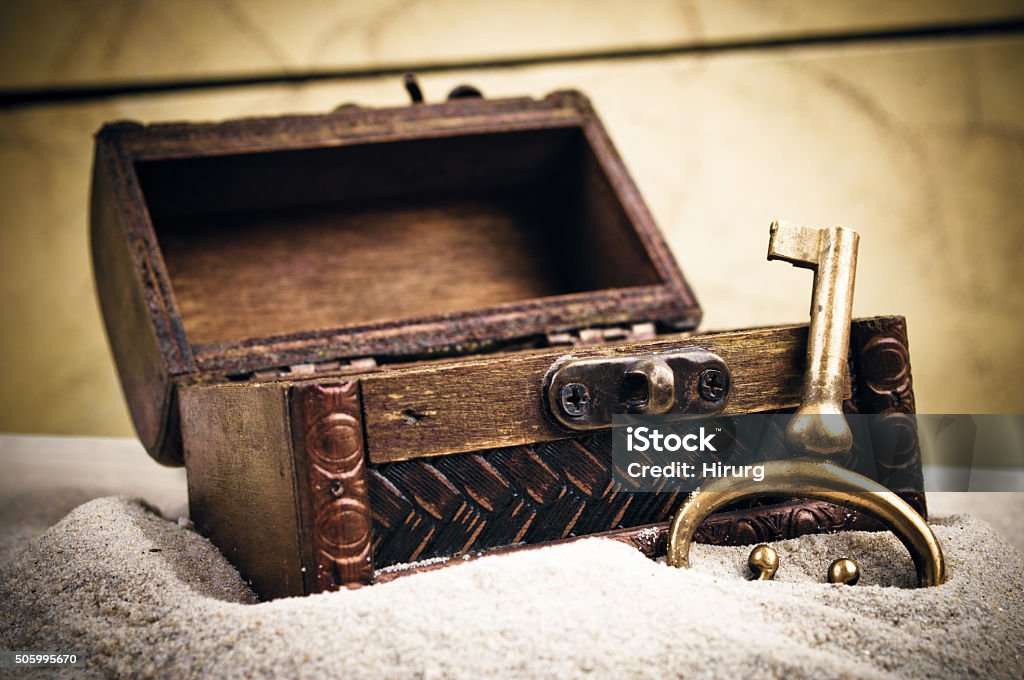Open wooden chest and metal key Open wooden chest and old golden metal key in the sand Treasure Chest Stock Photo