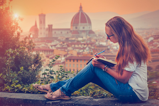 Young woman writing travel notes in Florence, Italy
