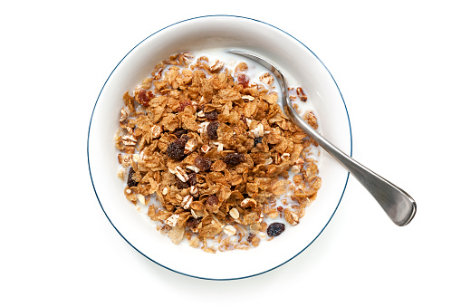 Bowl of cereal with spoon, isolated on white.  Overhead view.