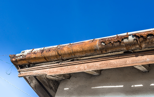 Rain gutters on old home. There is a blue sky in the background.