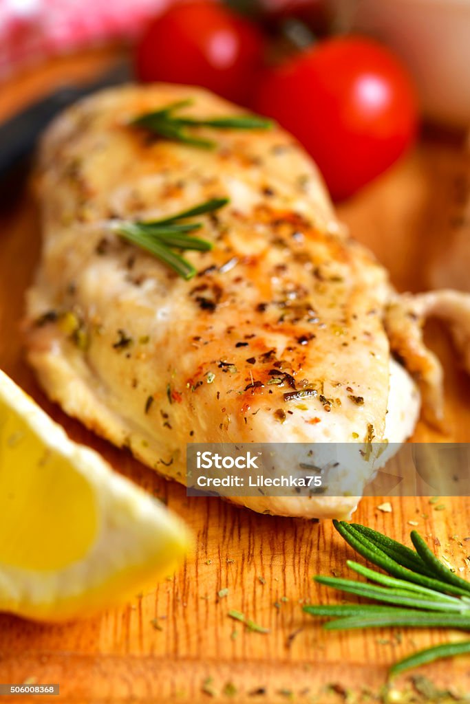 Chicken breast baked with rosemary. Chicken breast baked with rosemary on a cuuting board. Baked Stock Photo