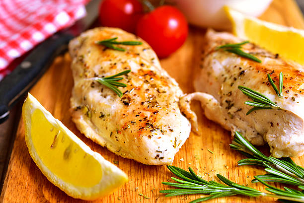 Chicken breast baked with rosemary. Chicken breast baked with rosemary on a cuuting board. Baked Chicken Breast stock pictures, royalty-free photos & images
