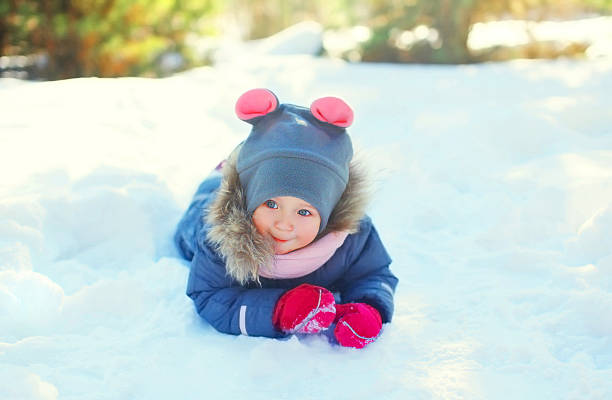 istock Happy little child lying playing on snow in winter day 506011066