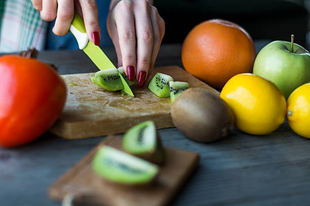 istock Woman's hands cuts fresh kiwi fruit 506019170