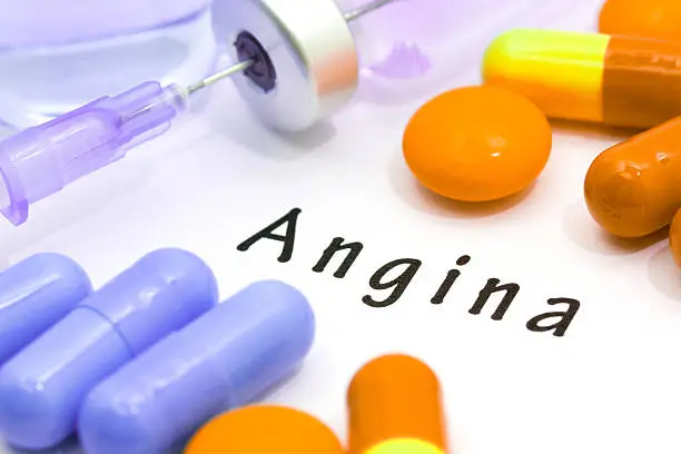 Word angina on a white background. An injection syringe and tablets.
