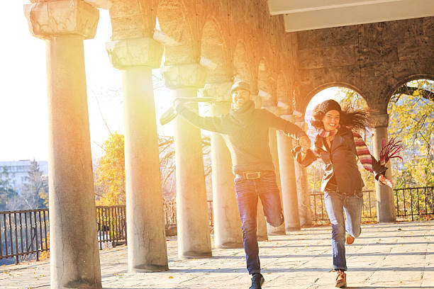 istock Young couple holding hands and jumping under ancient columns 506035300