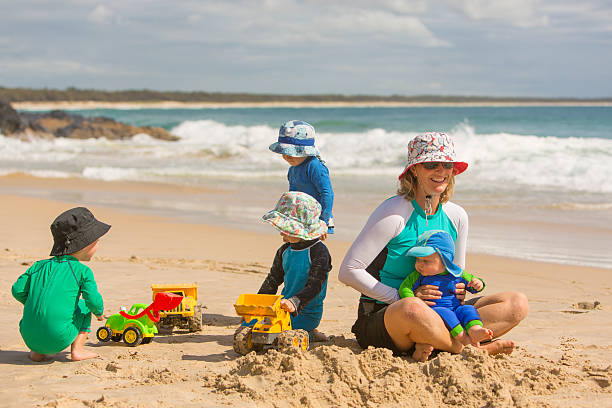 мать и мальчиков на пляже с солнечных лучей - lifestyles child beach digging стоковые фото и изображения