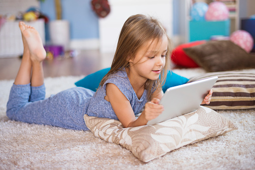 Little girl with digital tablet on the rug