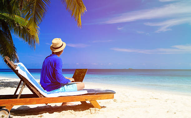 istock man with laptop on tropical beach 506039392
