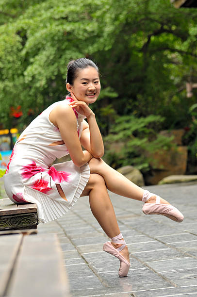 Closeup of ballerina's legs with her pink pointes shoes on. Ballet dancer is sitting on the gray stone steps. Dancer is resting on the stair. Dancer´s feet with pink ballet slippers on.
