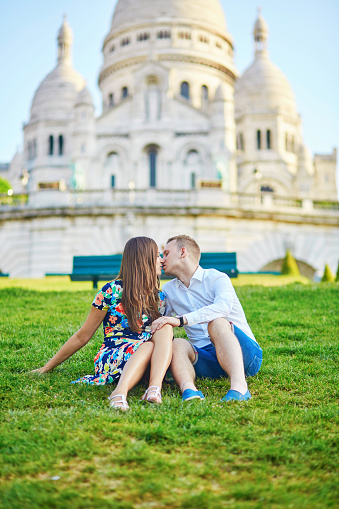 Romantic couple sitting together on the grass near Sacre-Coeur cathedral on Montmartre, Paris