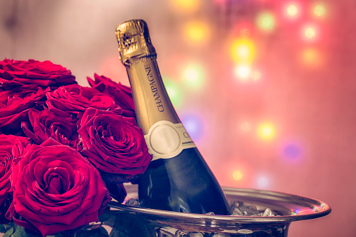 Romantic Bouquet of red Roses on festive background and a bottle of Champagne