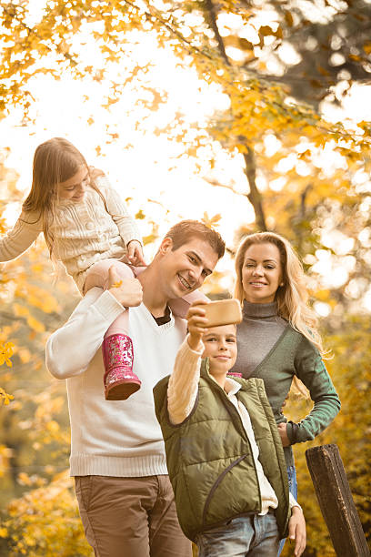 boy fotografiar su familia en el parque otoño - two parent family technology mobility men fotografías e imágenes de stock