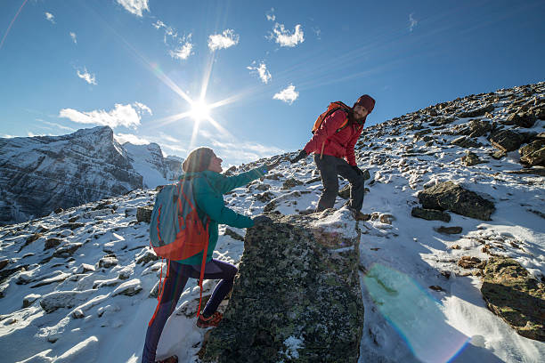 pareja de excursionistas ayudar - rocky mountains canada mountain winter fotografías e imágenes de stock