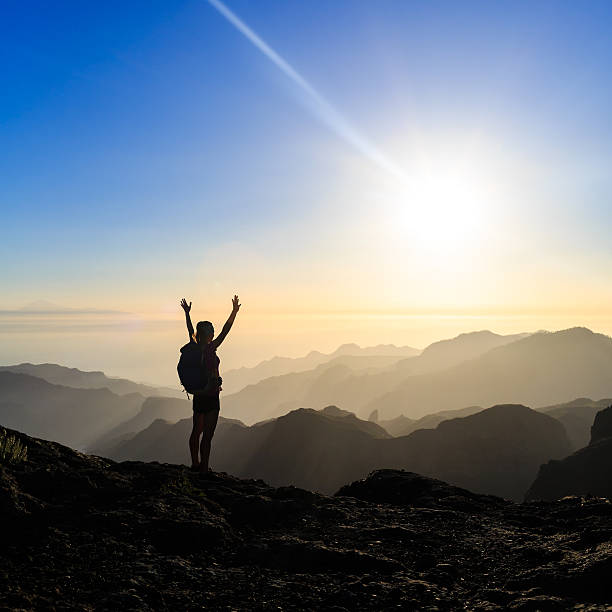 Woman hiking success silhouette in mountains sunset stock photo