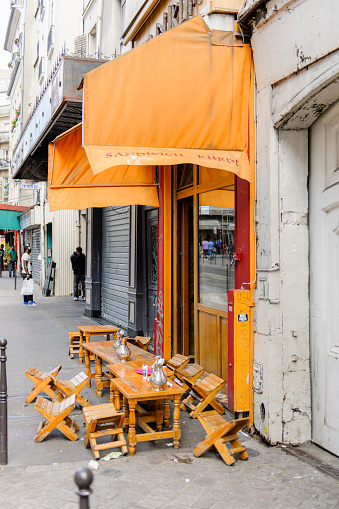 Paris, France - August 18, 2014: Street cafe with chairs on the streets of Paris, France with people talking at the mobile phone in the background