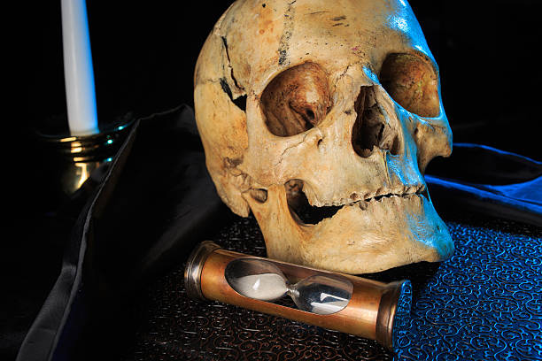 istock human skull on a book next to the clock. concept 506066586