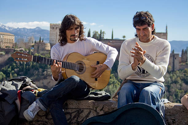 Granada, Spain - March 7, 2009: Flamenco street musicians entertaining people with flamenco music in Granada. They've got as background the Alhambra Palace
