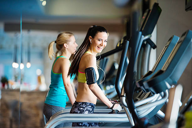 Beautiful women in gym Two young beautiful women working out in gym girl with headphones relaxing in the gym stock pictures, royalty-free photos & images