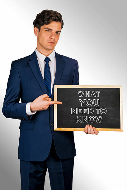 istock Young smiling businessman holding blackboard: Need To Know 506071324