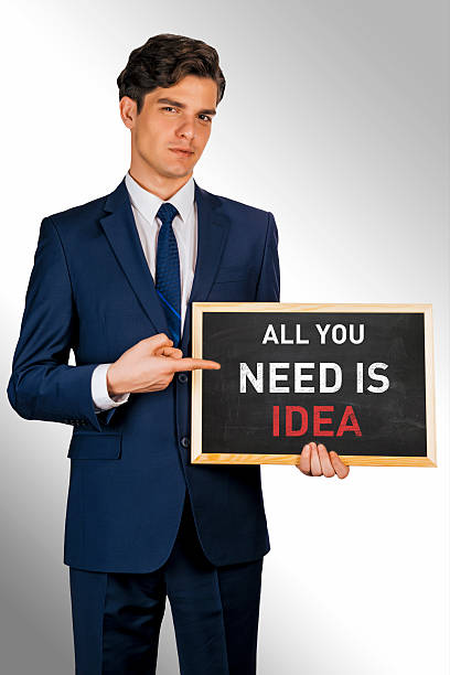 istock Young smiling businessman holding blackboard over white background: Idea 506071536