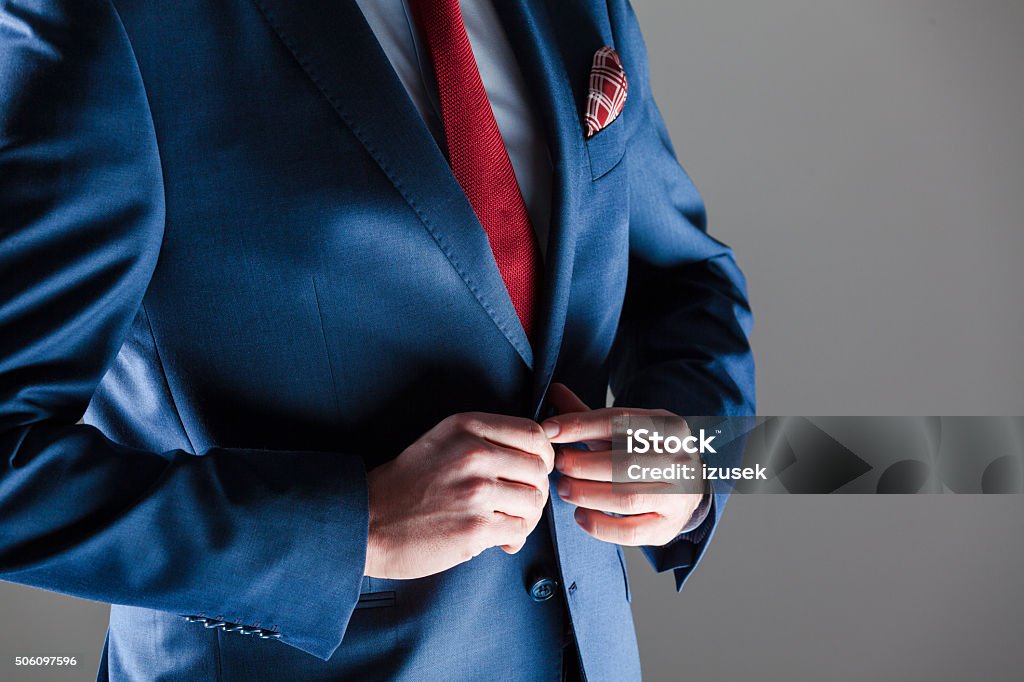 Male elegance, businessman wearing navy blue suit Close up of elegant busienssman wearing navy blue jacket, red tie and pocket square. Unrecognizable person, part of.  Close-up Stock Photo