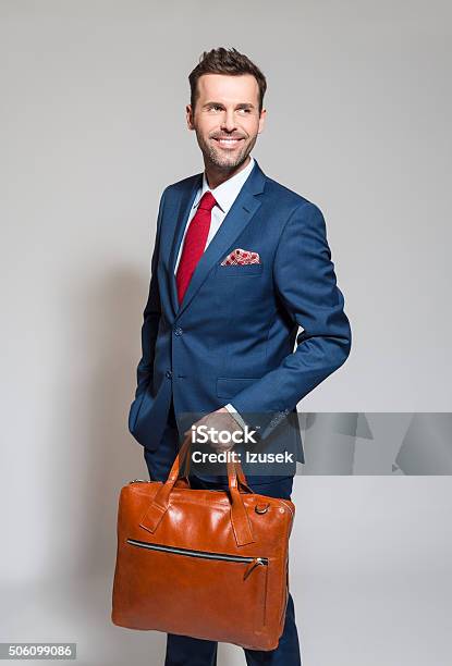 Confident Businessman Wearing Elegant Suit Holding Briefcase Stock Photo - Download Image Now
