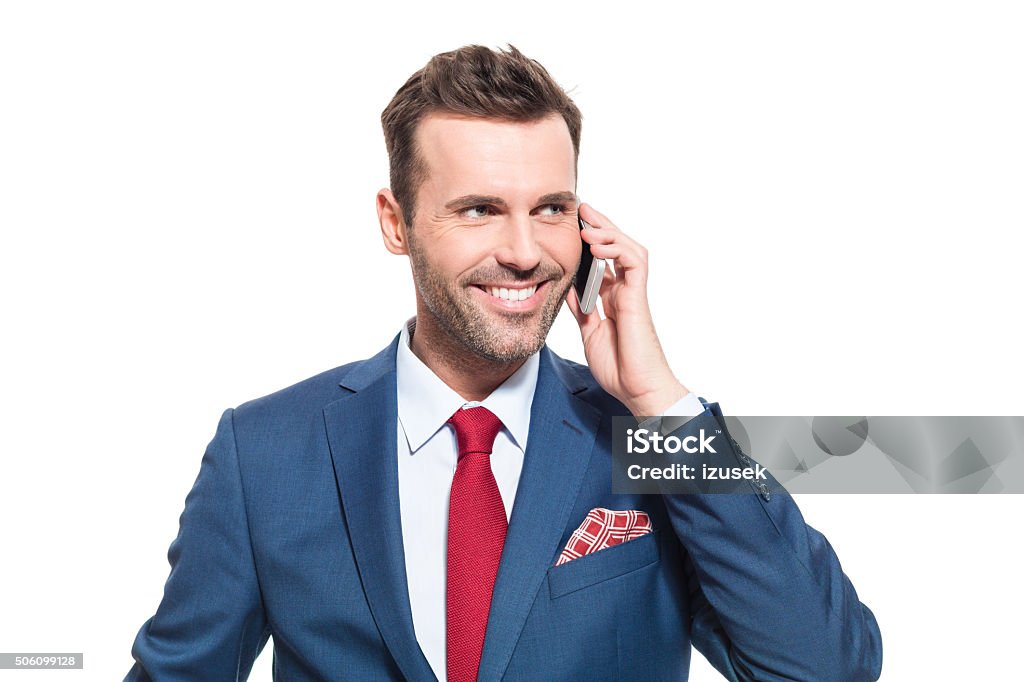 Successful businessman talking on smart phone Portrait of elegant businessman wearing elegant suit, talking on cell phone. Studio shot, one person, isolated on white. Adult Stock Photo