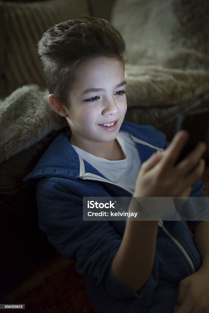 Мальчик улыбается на что-то на своем смартфоне - Стоковые фото Белый роялти-фри