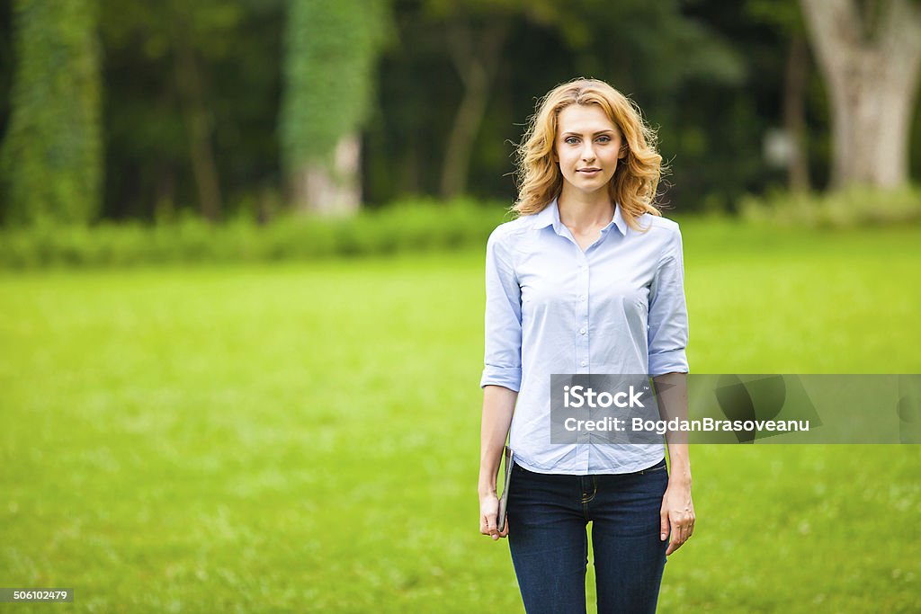 young lady with tablet in park young beautiful woman with tablet in hand, in walking in the park Adult Stock Photo