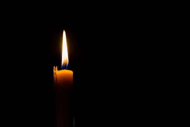 Photo of Yellow candle on the dark background