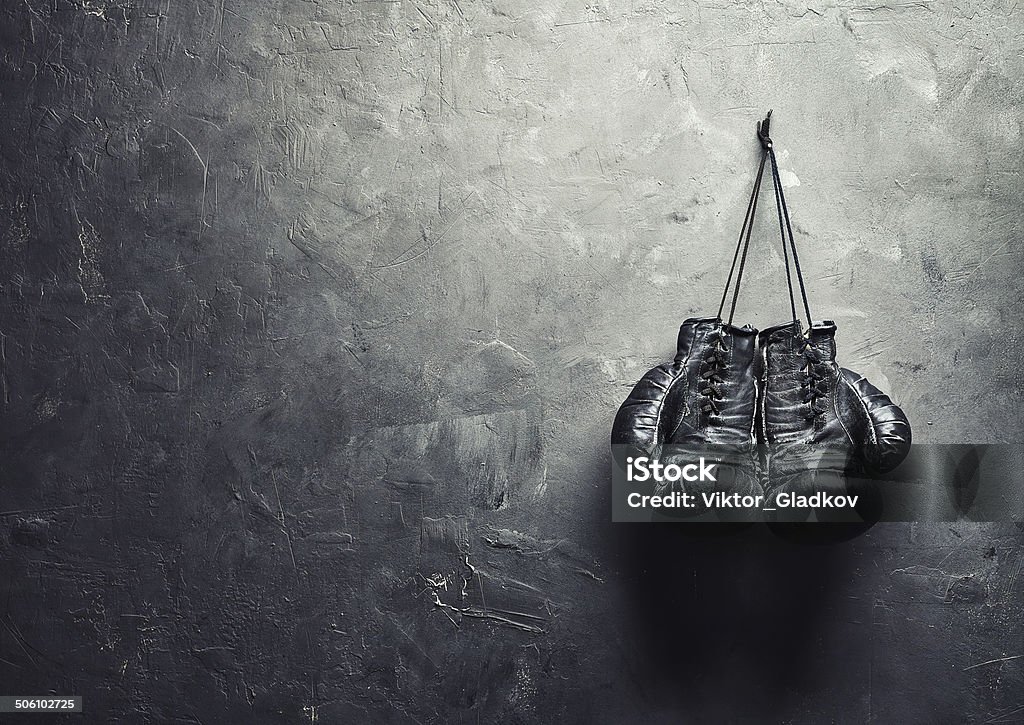 old boxing gloves nailed to the textured wall old boxing gloves hang on nail on texture wall with copy space for text. Retirement concept Boxing Glove Stock Photo