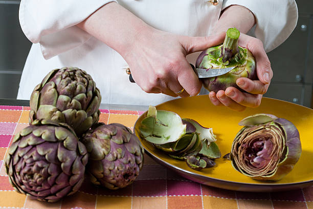 Preparing Jewish artichokes Hands clean and cut fresh Roman artichokes on a colorful background artichoke stock pictures, royalty-free photos & images