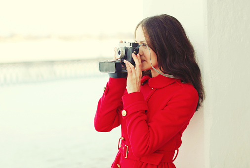 Beautiful young woman with retro vintage camera in winter day, profile view