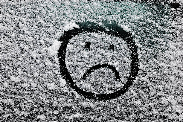 istock sad smiley face drawn on snow-covered glass. 506106622