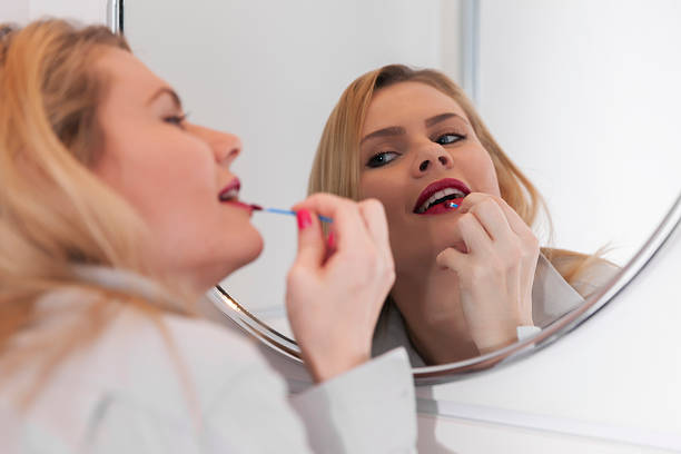 istock Young woman applying lipstick in front of mirror 506106908
