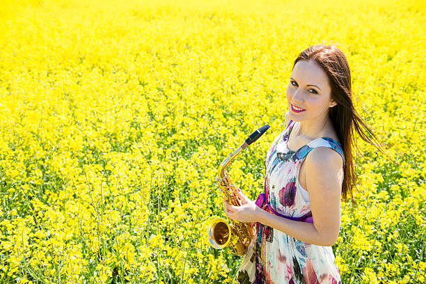 Woman with saxophone in rapeseed field