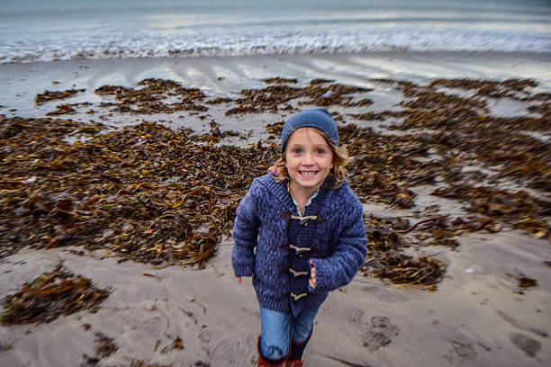 Beach Girl Happy young lady runs confidently toward the camera on a seweed filled beach in blustery Ireland low tide stock pictures, royalty-free photos & images