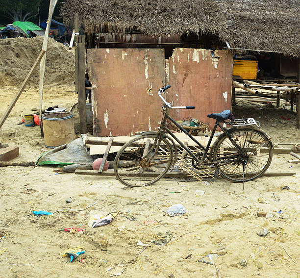 Old beat up bicycle in poverty stricken area with trash and dirt and old buildings located on Irrawaddy River Bank in Mandalay Myanmar