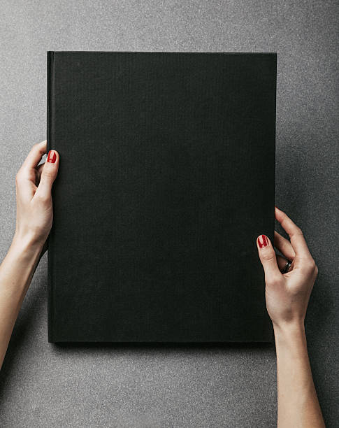 istock Female hands holding big black book. Vertical 506123622