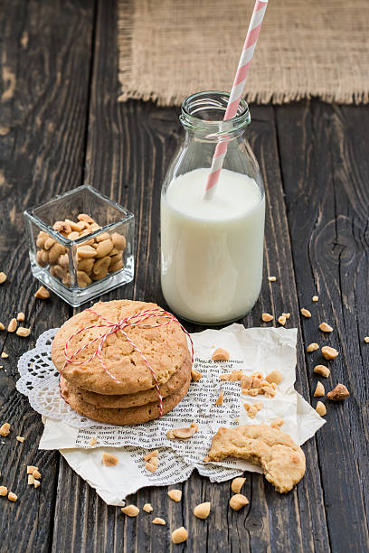 beurre de cacahuètes cookies, lait et cacahuètes sur une surface en bois sombre - nobody food canvas peanut photos et images de collection