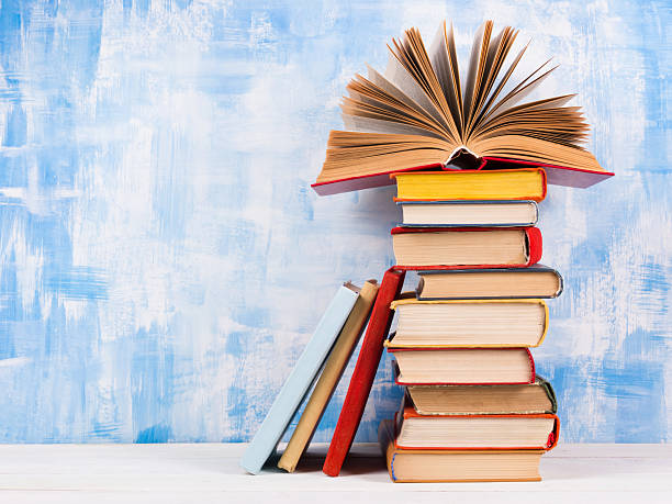 istock Stack of colorful hardback books, open book on blue background 506130502