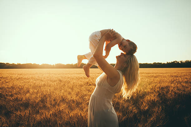 Mom and son Mom and son having fun by the lake, field outdoors enjoying nature. Silhouettes on sunny sky. Warm filter and film effect mini wheat cereal stock pictures, royalty-free photos & images