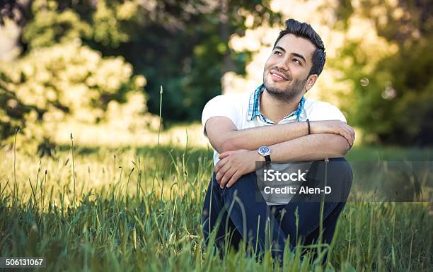 Happy Young Man Sitting On Meadow Stock Photo - Download Image Now - Latin American and Hispanic Ethnicity, Looking Up, 20-29 Years